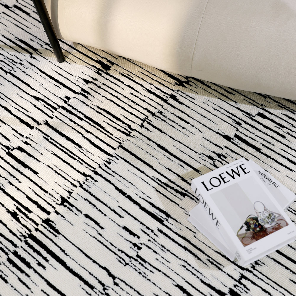 Textured black and white Shattered Illusions rug under a chair with a magazine.