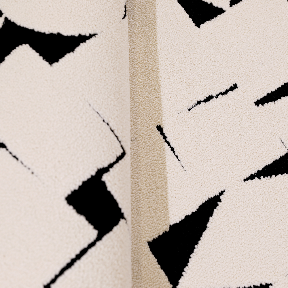 Close-up of modern cream rug with black abstract geometric patterns