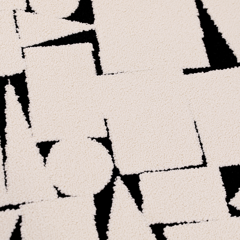 Modern rug with abstract black geometric shapes on cream background