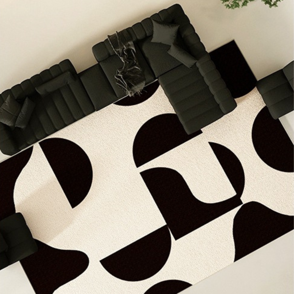 Black and cream Modulo geometric washable rug under a modern black sofa.