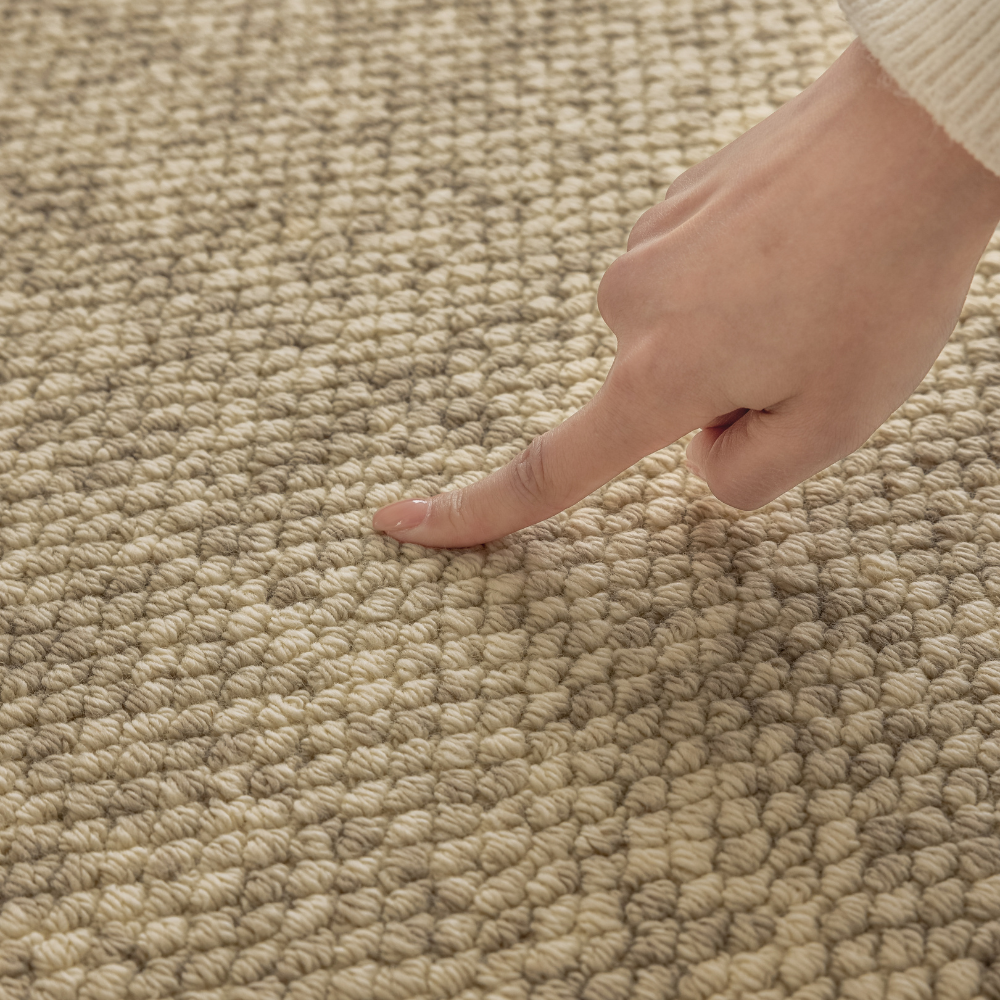 Close-up of Golden Path Soft Woven Rug texture with a hand pointing