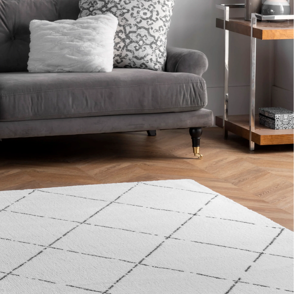 Washable geometric rug with diamond pattern in white and black in a cozy living room.