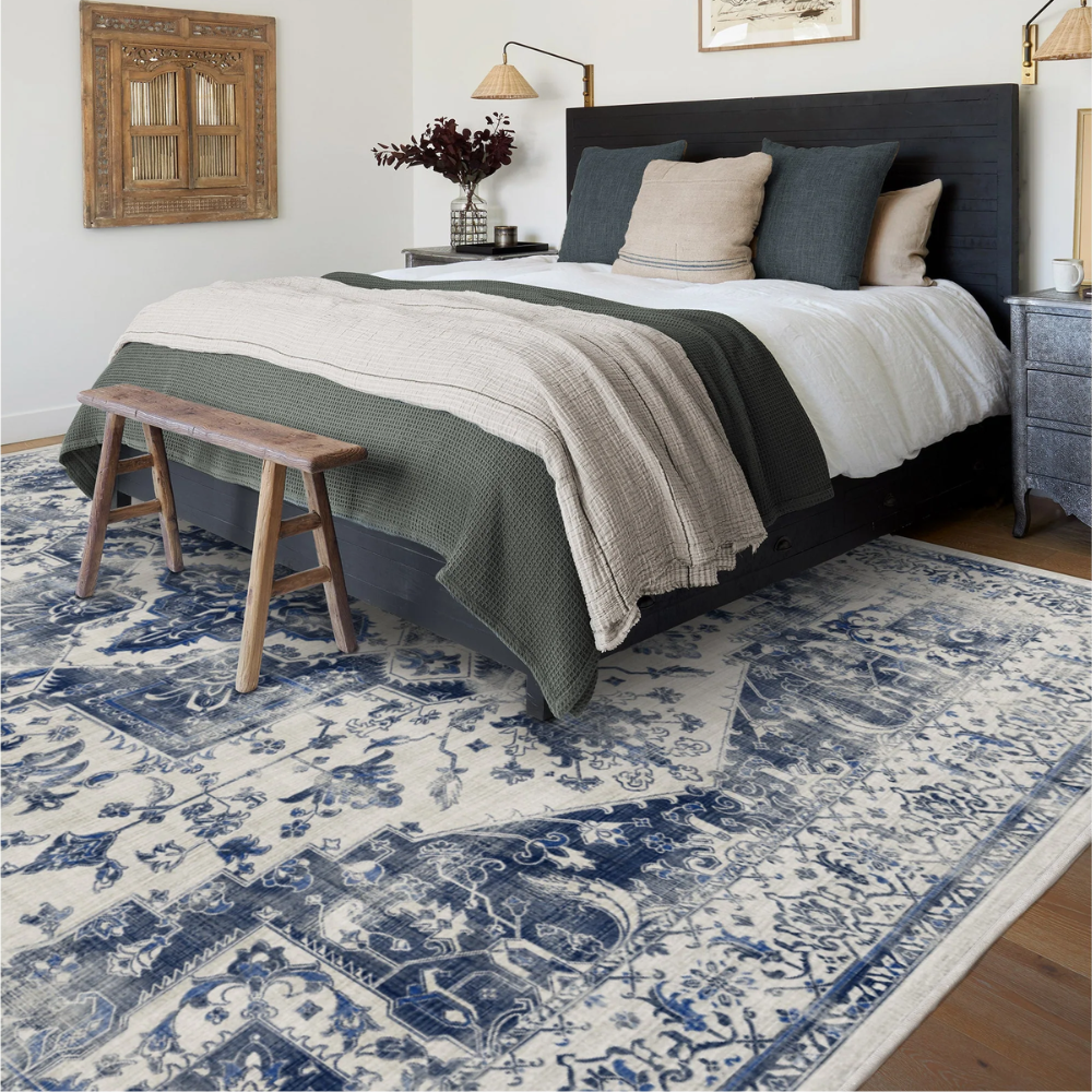 Blue and white floral Marina Persian washable rug under a bed in a cozy bedroom