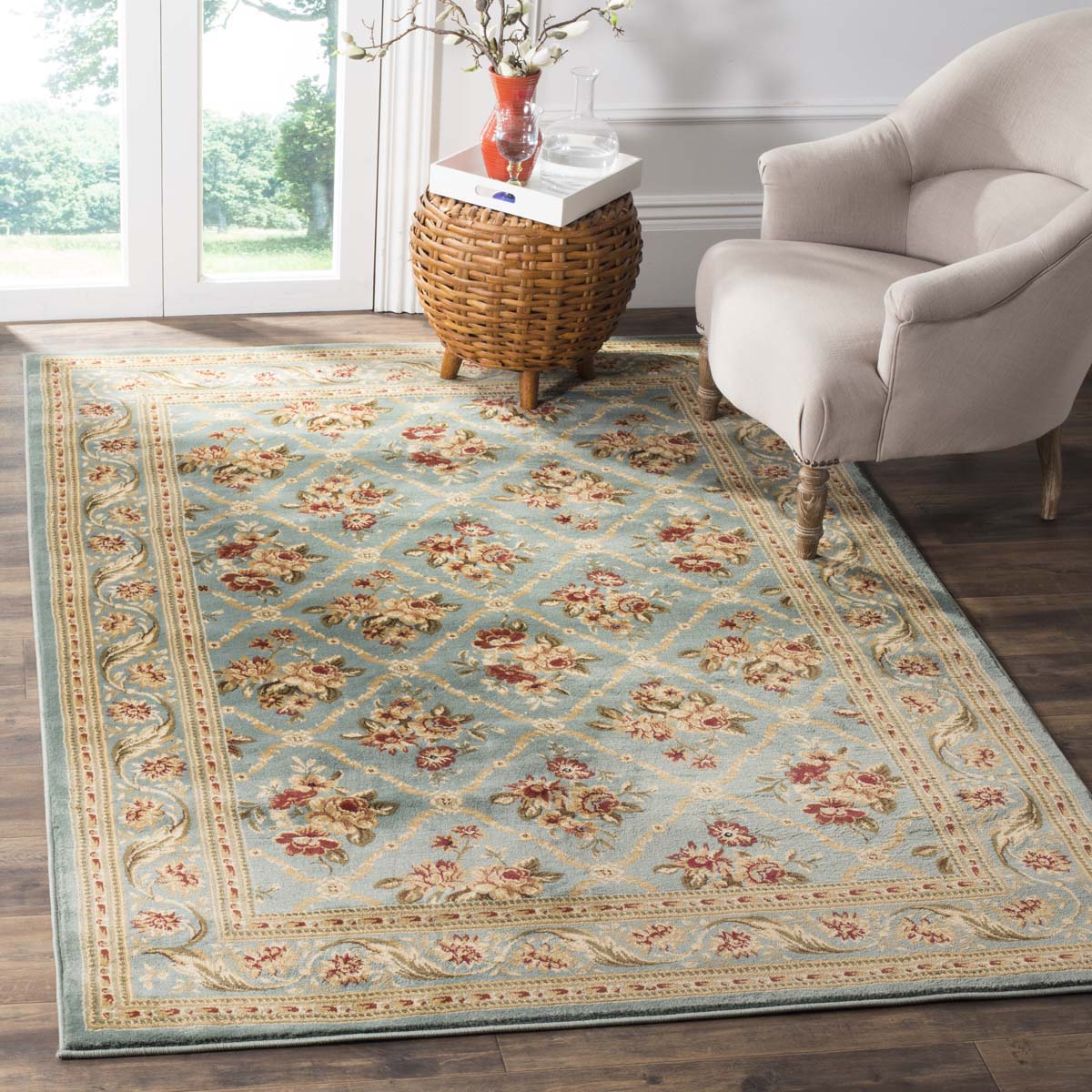 Vintage floral area rug in blue with red and gold accents in a bright living room