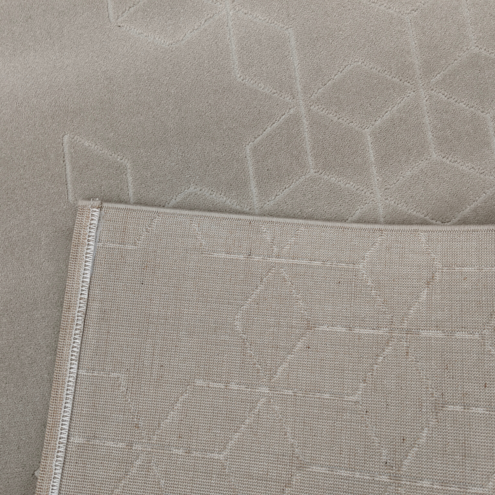 Close-up of neutral Peregrine geometric rug with hexagonal texture and folded edge