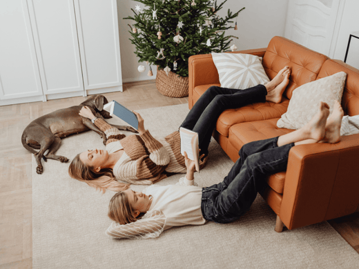 A family relaxes on a bedroom rug with a Christmas tree in the background