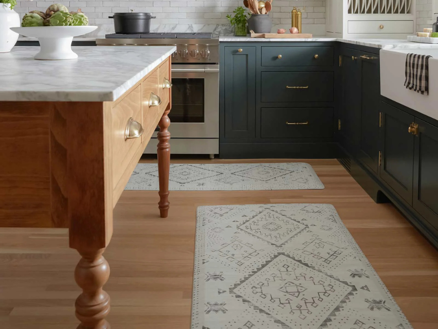 A rustic kitchen featuring a patterned area rug that matches the wooden island and dark cabinetry.