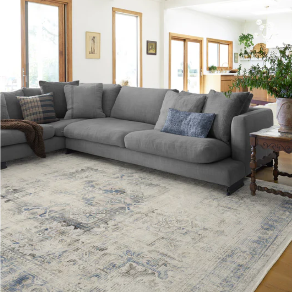 Vintage washable rug in blue and cream tones under a gray sectional sofa